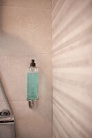 Baño con ducha, dispensador de jabón para manos y manguera de ducha.