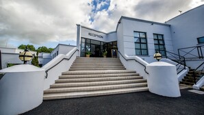 A reception area with a staircase leading to the entrance, surrounded by white walls and potted plants. - Waterfoot Hotel (Londonderry)