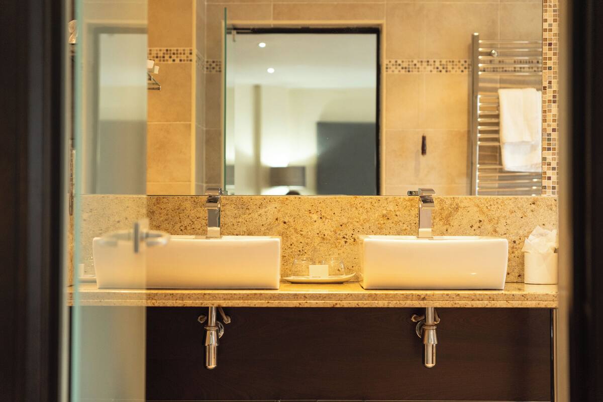 A bathroom with a double sink, a mirror, and a towel rack.