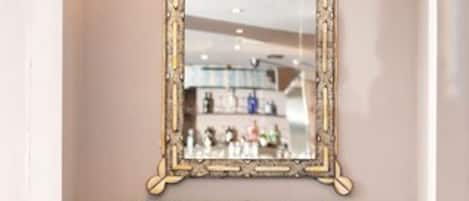 A blue tufted armchair with a gold-framed mirror above it.
