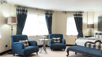 A hotel room with a bed, two armchairs, a small table, and a lamp.