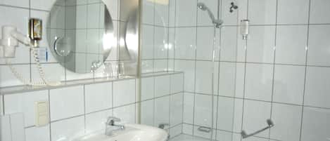 Une salle de bain moderne avec un lavabo blanc, un miroir et une douche à parois de verre.