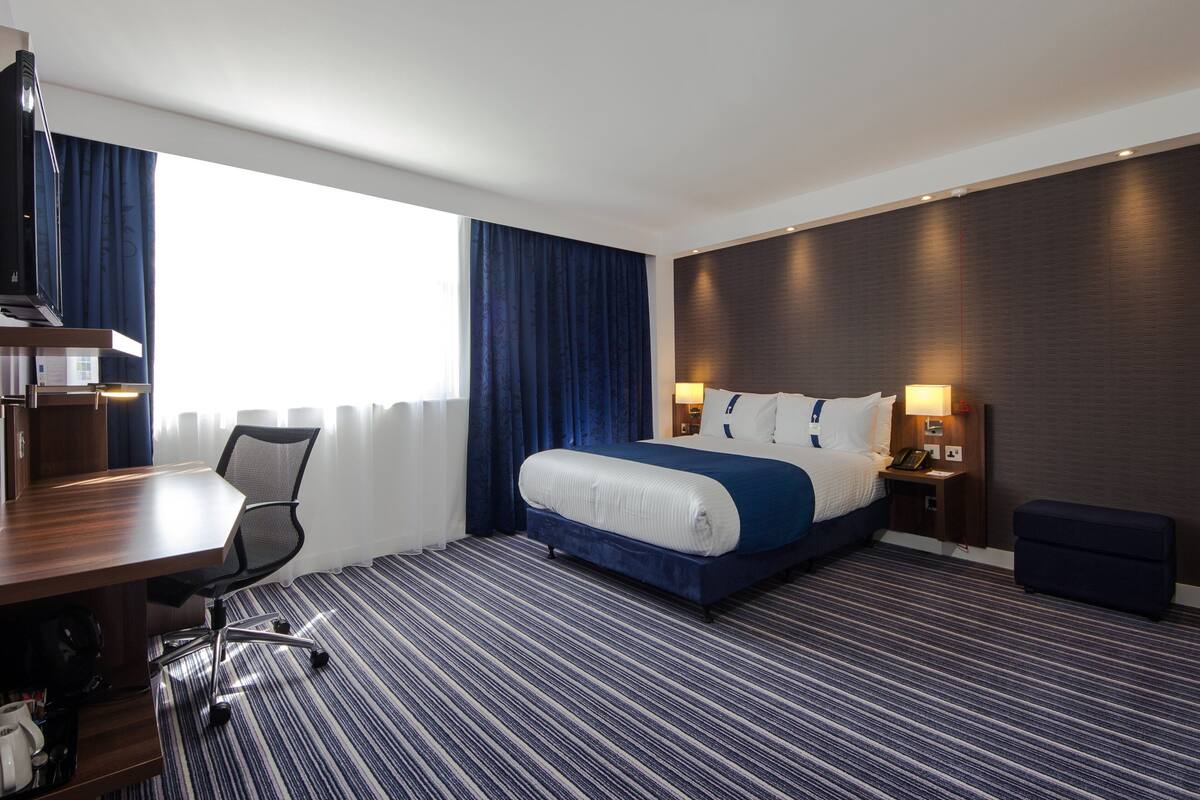 Una habitación de hotel con una cama grande, un escritorio y una silla.