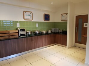 A kitchen with a buffet setup, including a coffee machine and food containers on the counter.