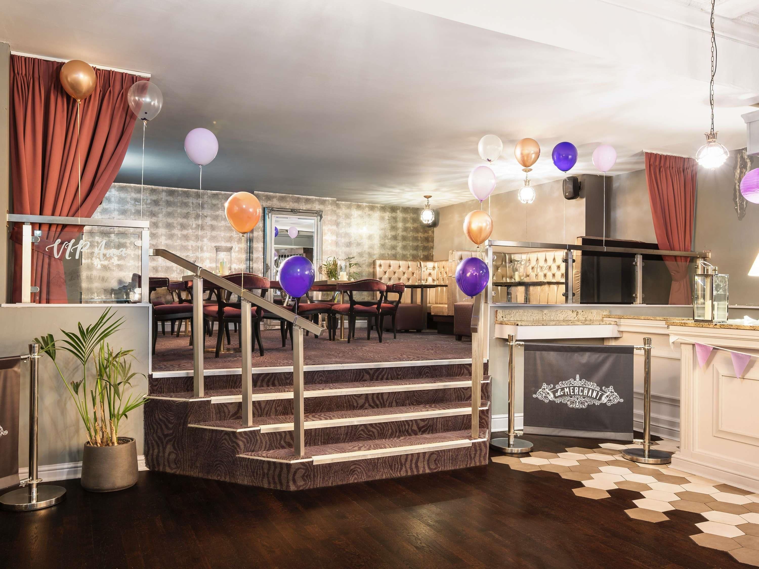 A modern interior with a staircase, dining area, and bar.