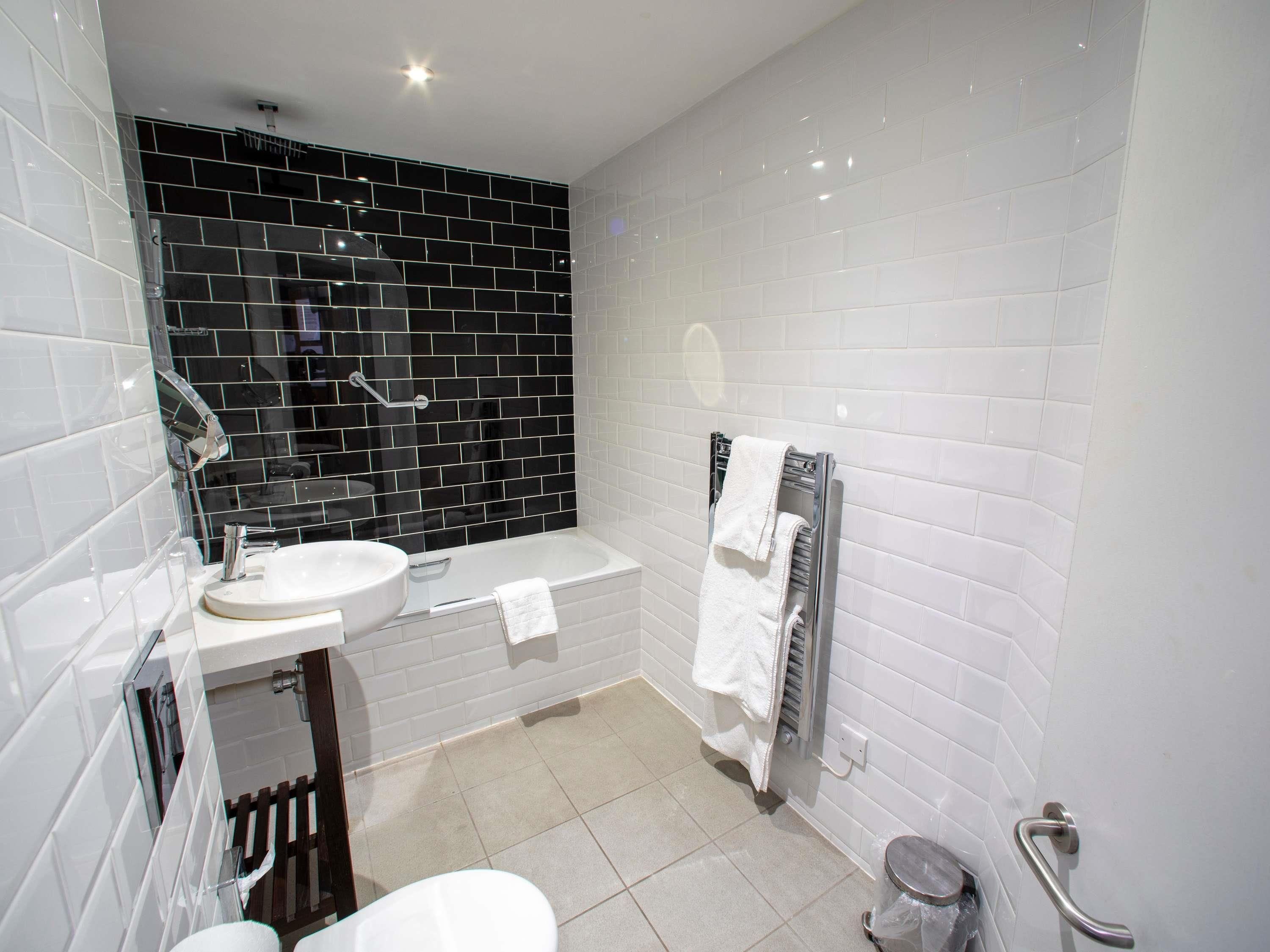A modern bathroom with a white sink, a bathtub, and a toilet.