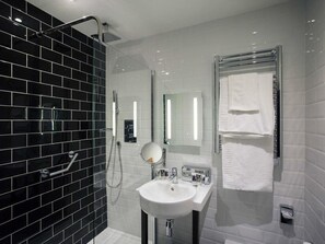 A modern bathroom with a black tiled shower wall, a white sink with a mirror, and a towel rack. - Mercure Doncaster Centre Danum Hotel (Doncaster)