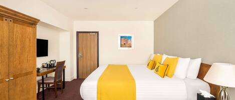 A hotel room with a bed, a desk, a chair, a wardrobe, and a television.