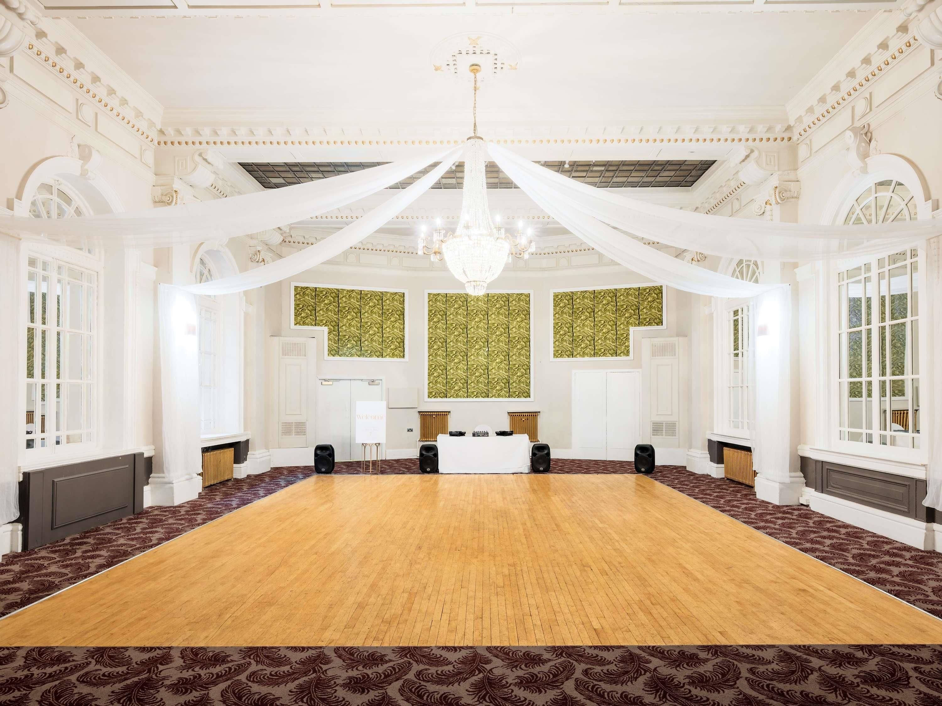 A large conference room with a long table, white drapery, and a chandelier.