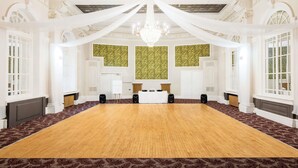A large conference room with a long table, white drapery, and a chandelier. - Mercure Doncaster Centre Danum Hotel (Doncaster)