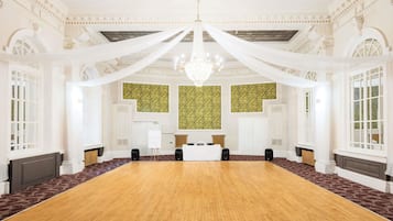 A large conference room with a long table, white drapery, and a chandelier.
