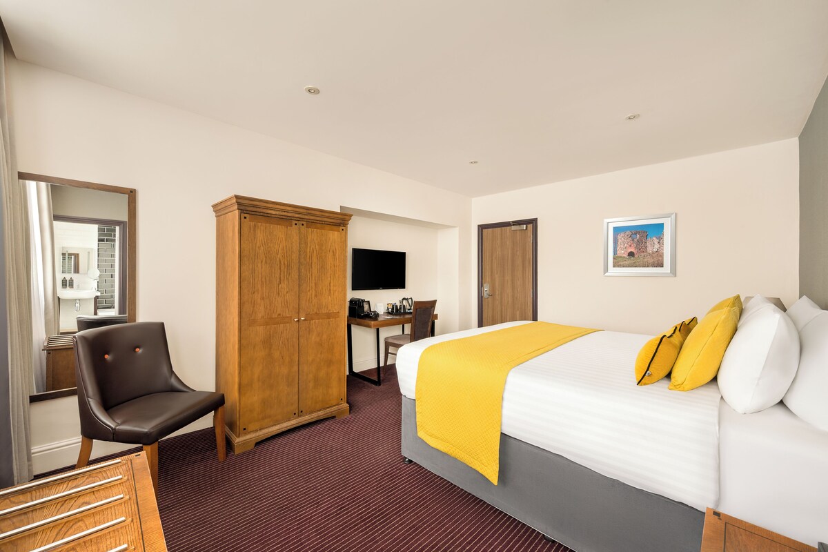 Ein Hotelzimmer mit Bett, Schreibtisch, Stuhl und Kleiderschrank.