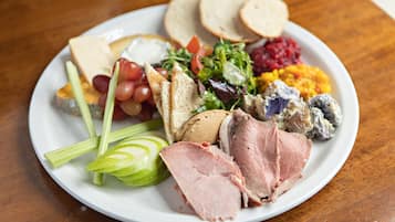 Un plato con una variedad de alimentos, entre ellos jamón en rodajas, queso, uvas y diferentes ensaladas.