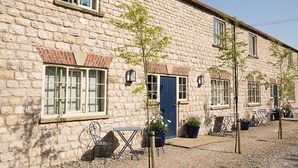 A stone building with a blue door, windows, and outdoor seating with potted plants. - The White Swan Inn (Pickering)