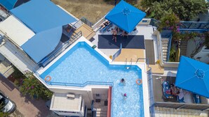 Una piscina en la azotea con agua cristalina, rodeada de sillas de descanso y sombrillas.