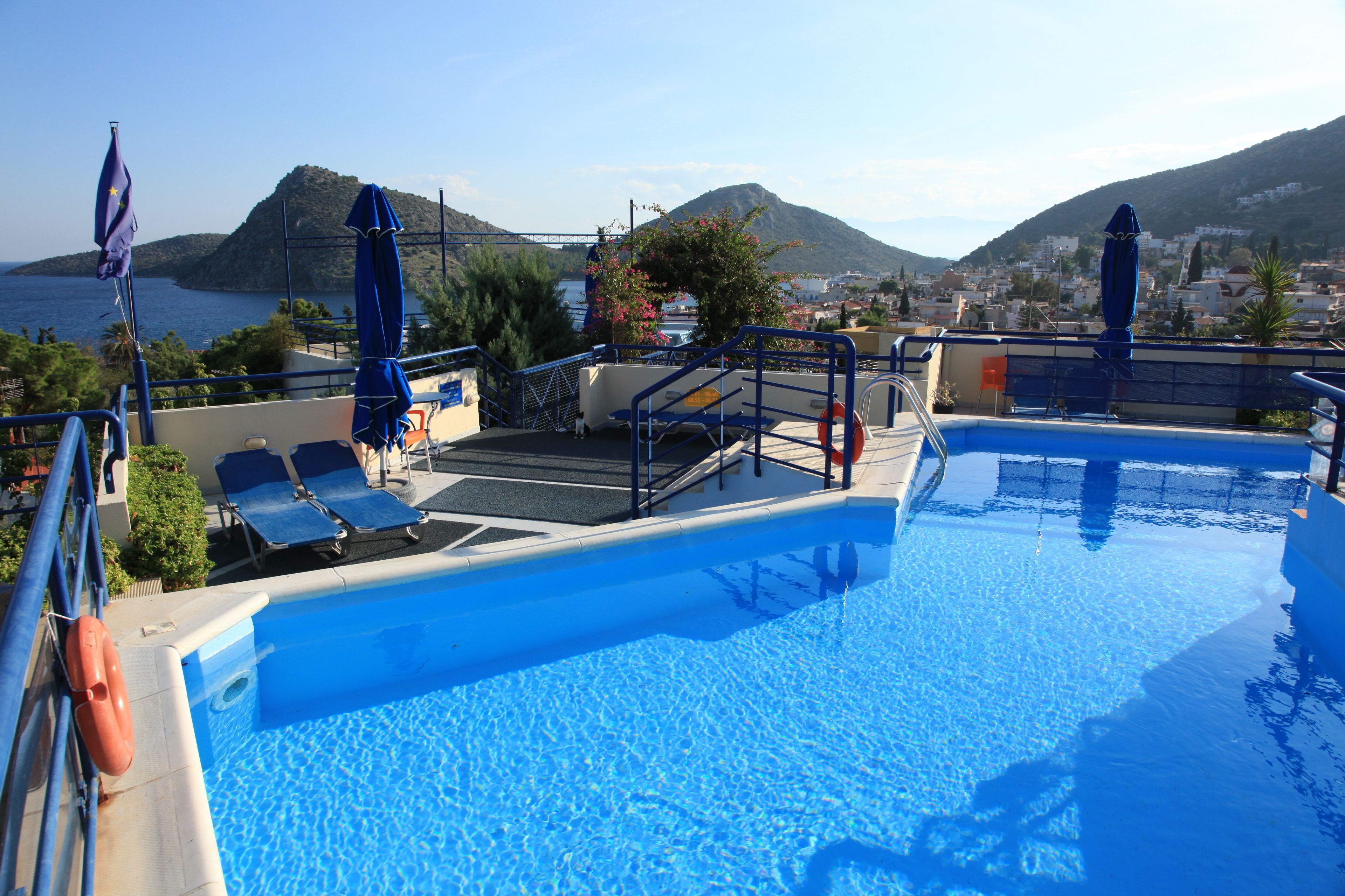 A swimming pool with blue water, sun loungers, and umbrellas.