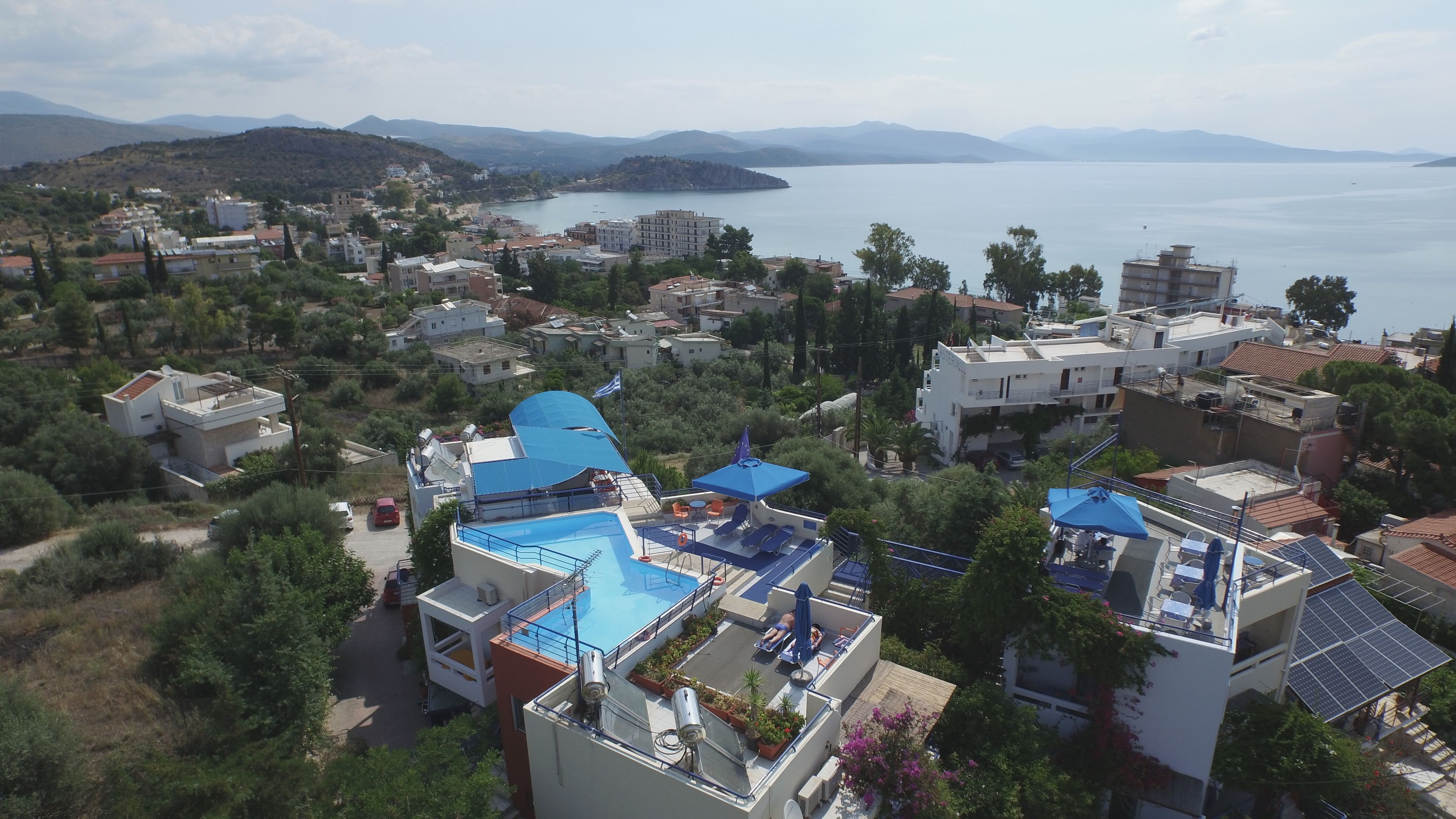 A residential area with a swimming pool on a rooftop, surrounded by houses and a view of the sea.