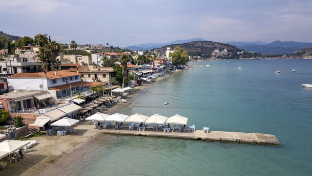 Un pueblo costero con playa, aguas cristalinas y barcos.