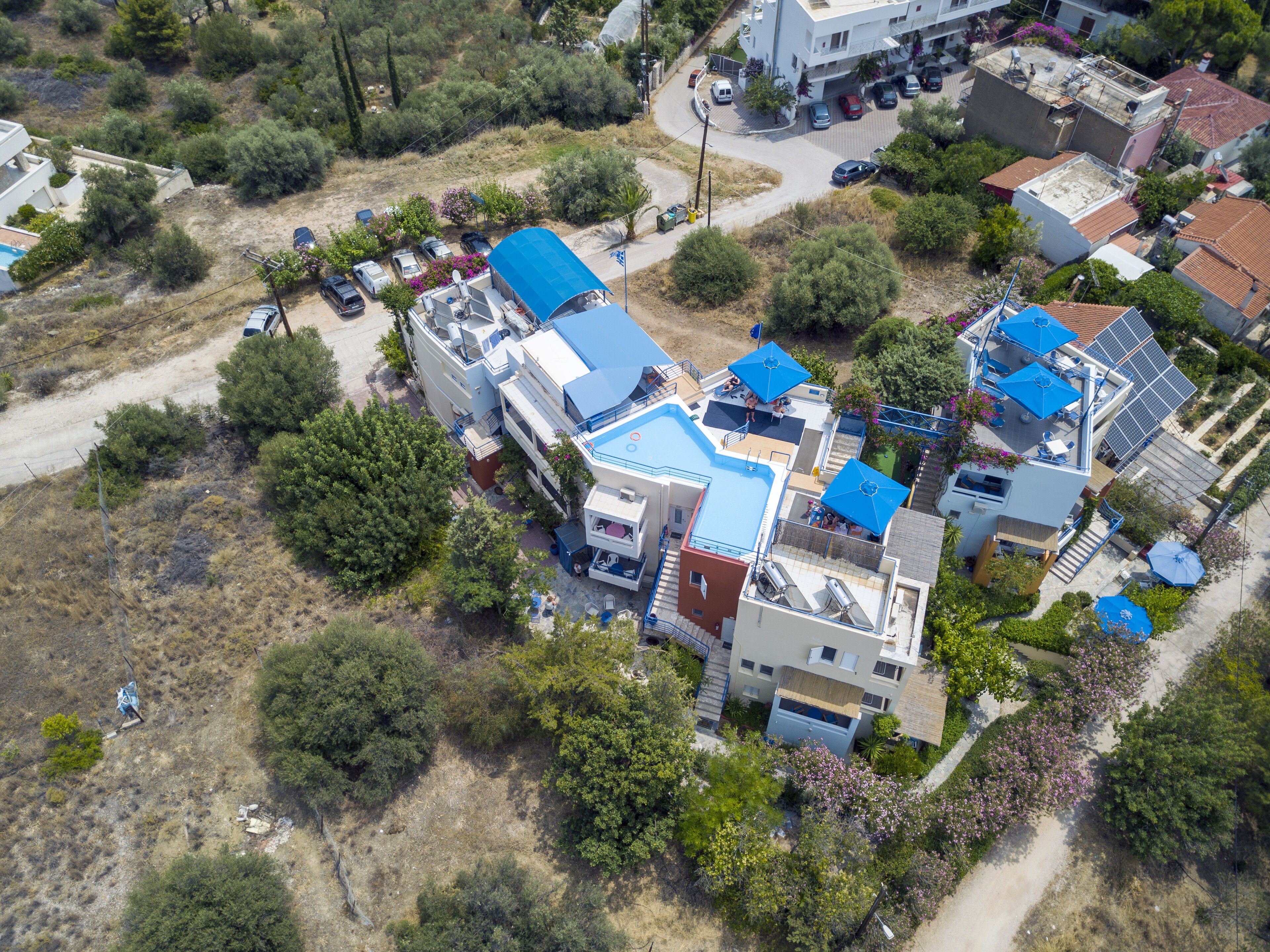 An aerial view of a residential area with modern houses, a swimming pool, and solar panels.