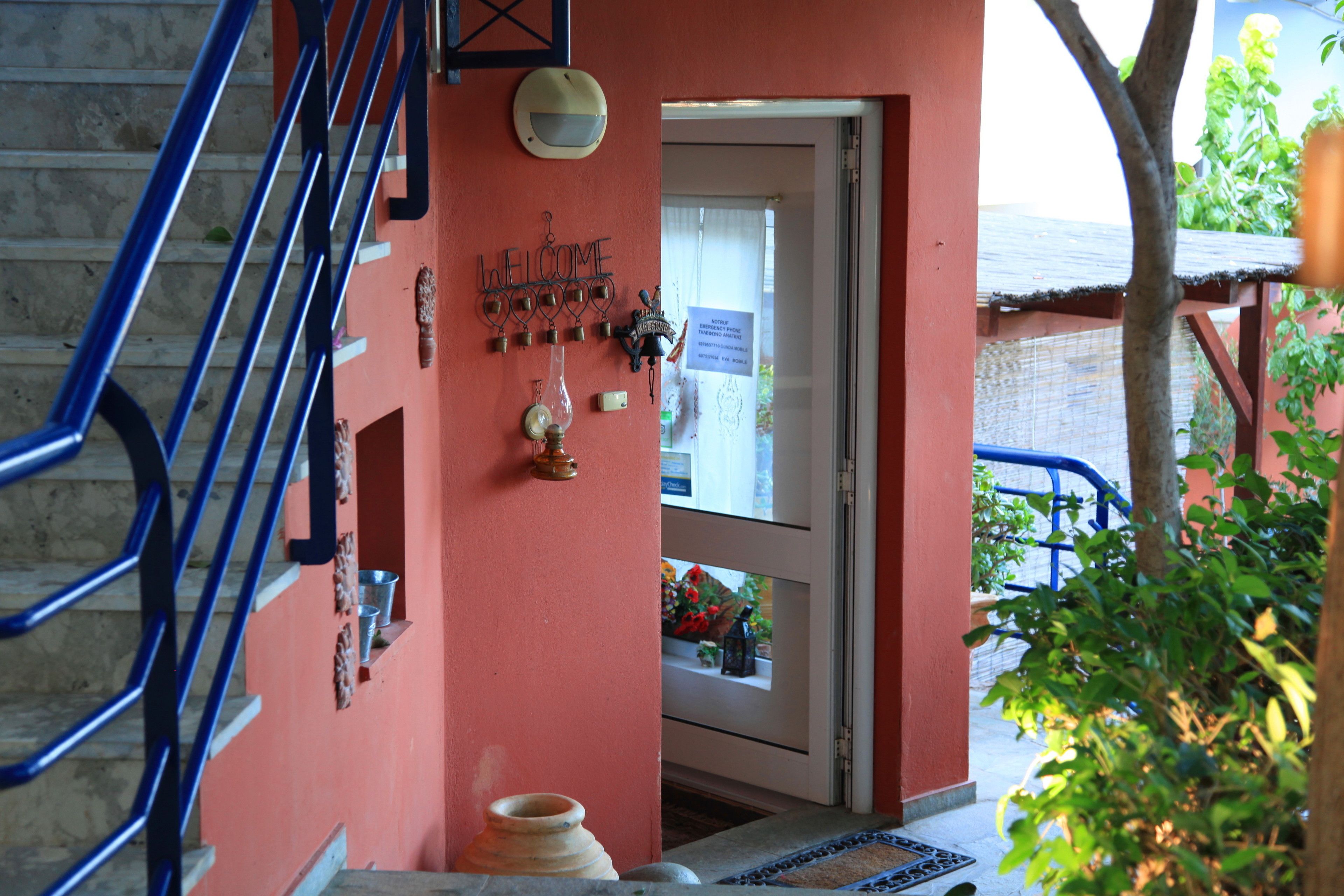 A staircase with blue railings leading to a door with a 'Welcome' sign.