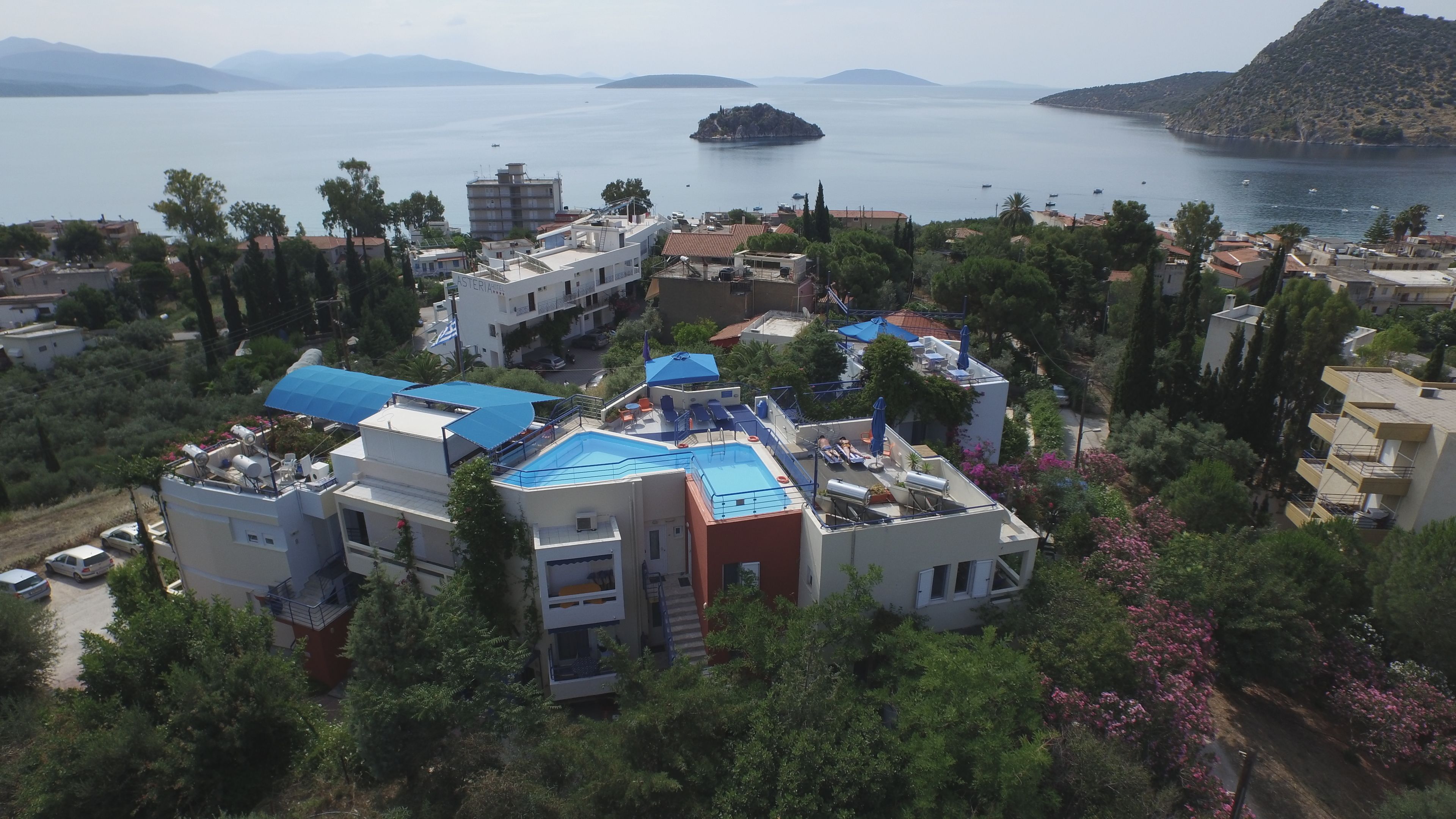A coastal residential area with modern buildings, a swimming pool, and a view of the sea and a small island.