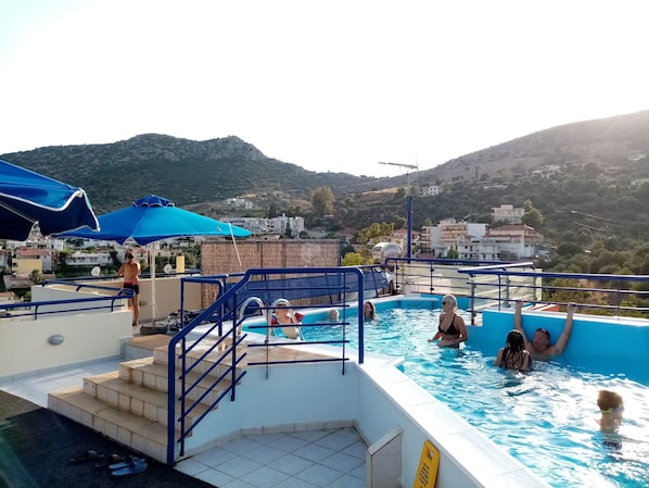 Una piscina al aire libre, sombrillas, sillones reclinables de piscina