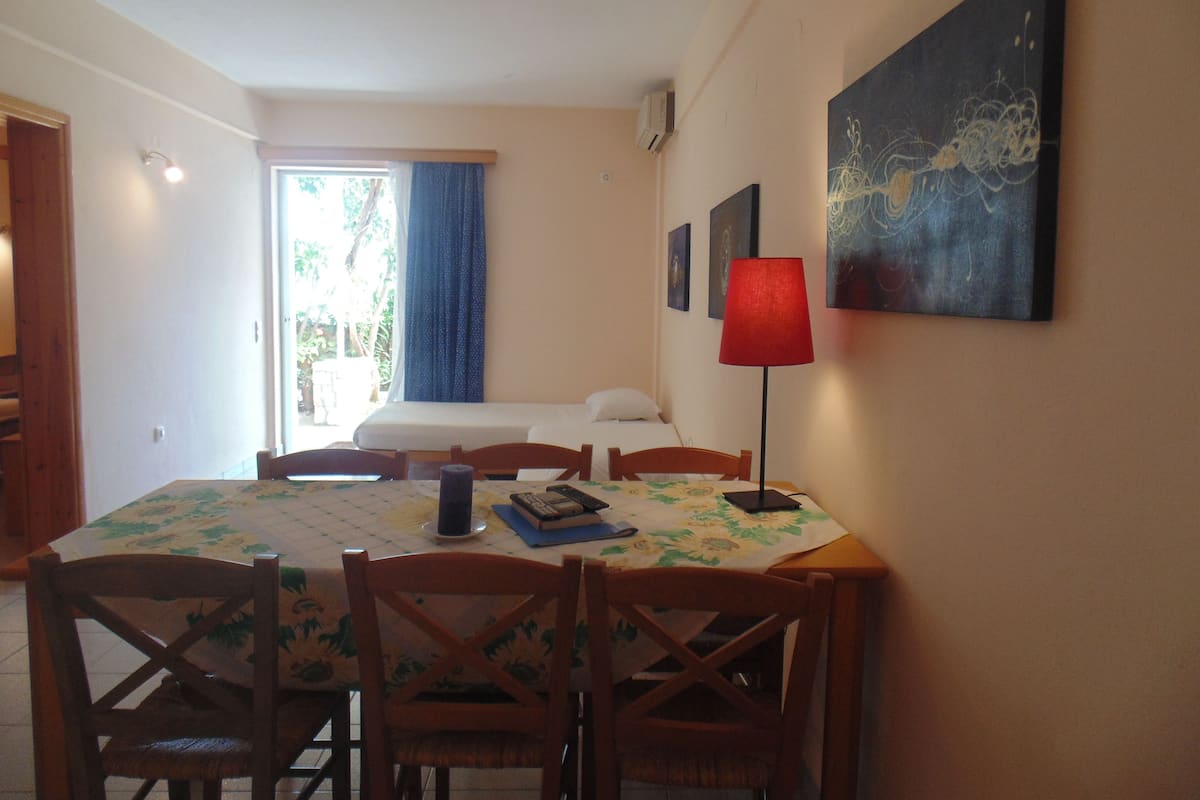 Une pièce comprenant un lit, une table à manger avec des chaises, une lampe rouge et des œuvres d’art accrochées au mur.