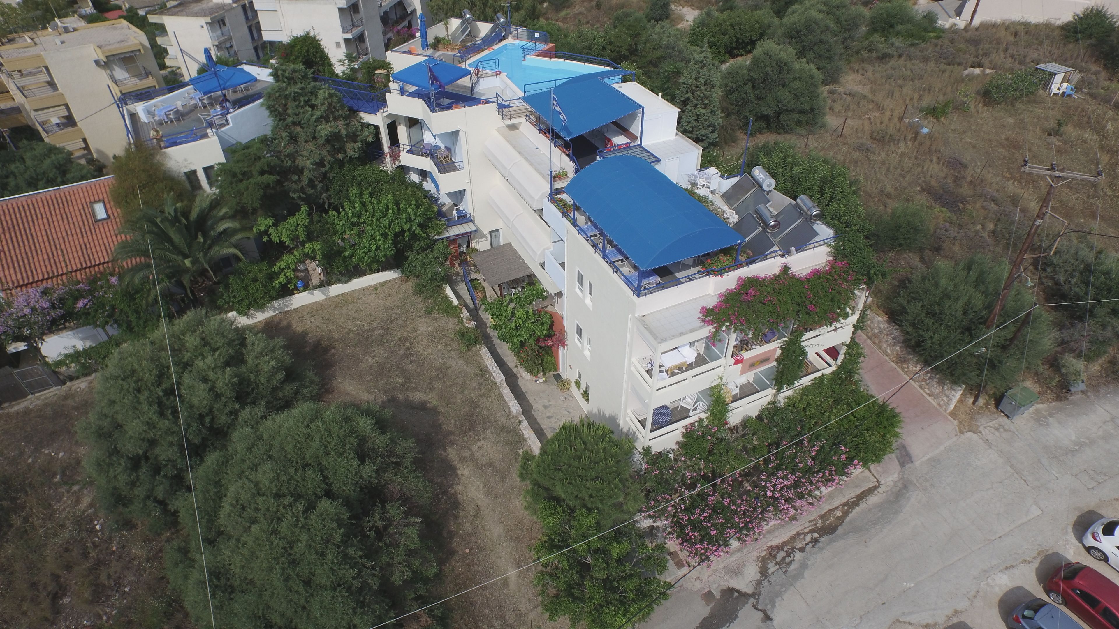 Vista aérea de un edificio de varios pisos con piscina, balcones y follaje circundante.