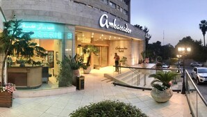 A hotel entrance with a sign reading "Ambassador Hotel" and a neon sign for "Keith Jarrod SERVE". - Ambassador Hotel (Jerusalem)