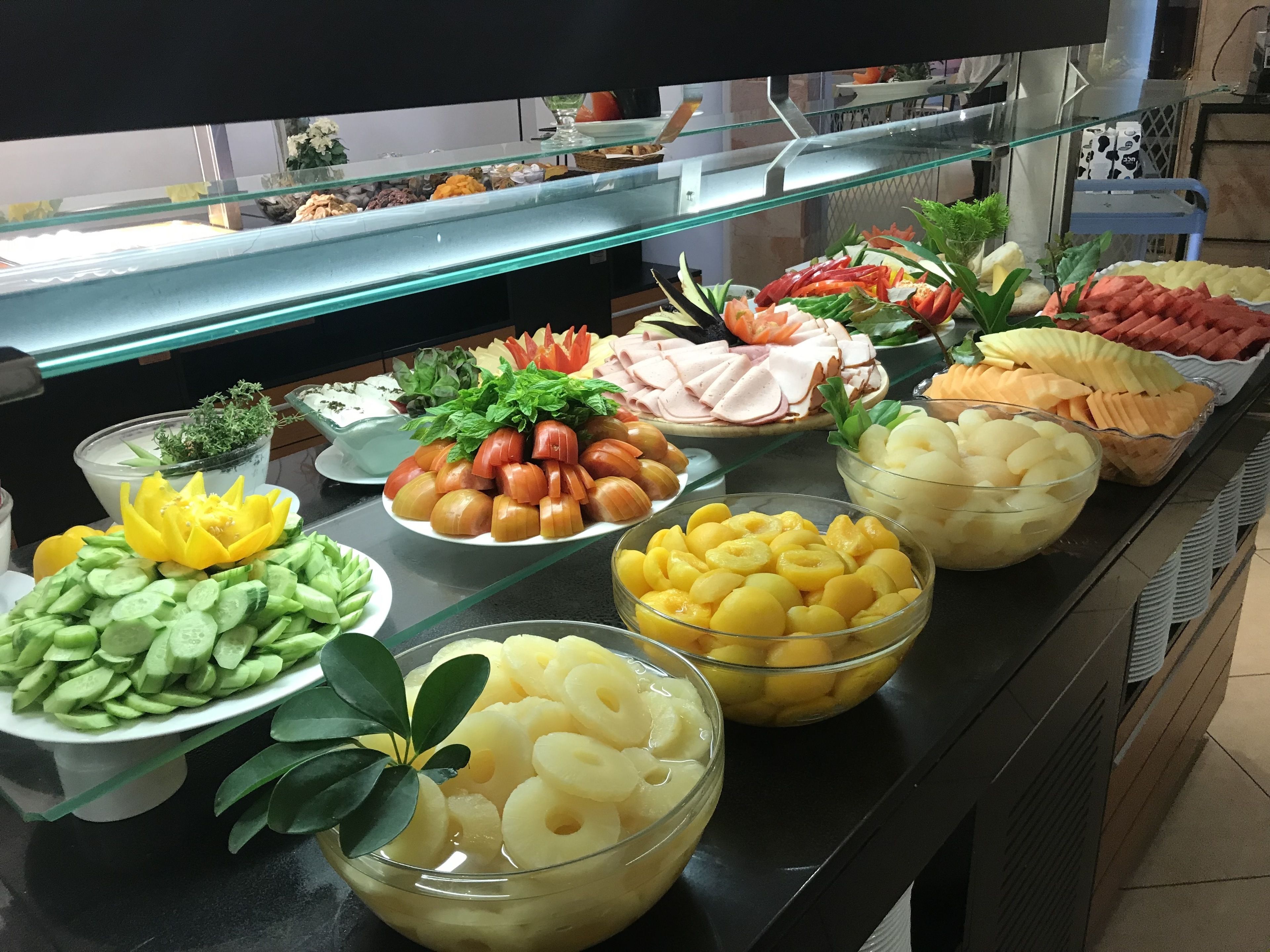 Un bufé con diversos alimentos, como frutas en rodajas, verduras y carnes.