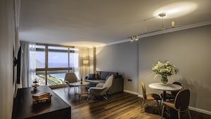 Una sala moderna con sofá, sillas, una mesa de comedor y vistas al océano.