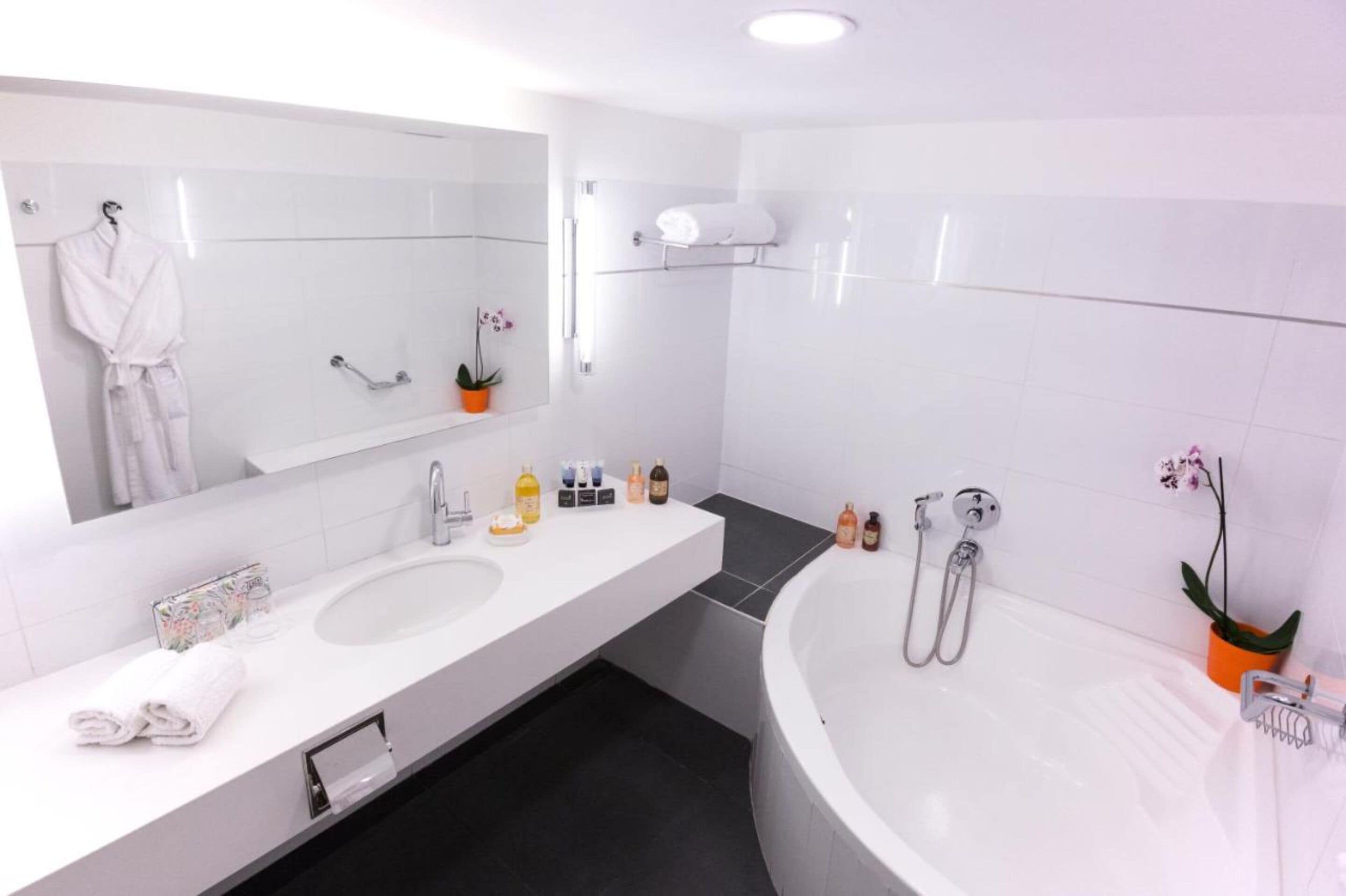 Une salle de bain moderne avec un grand miroir, deux lavabos, une baignoire et une douche.