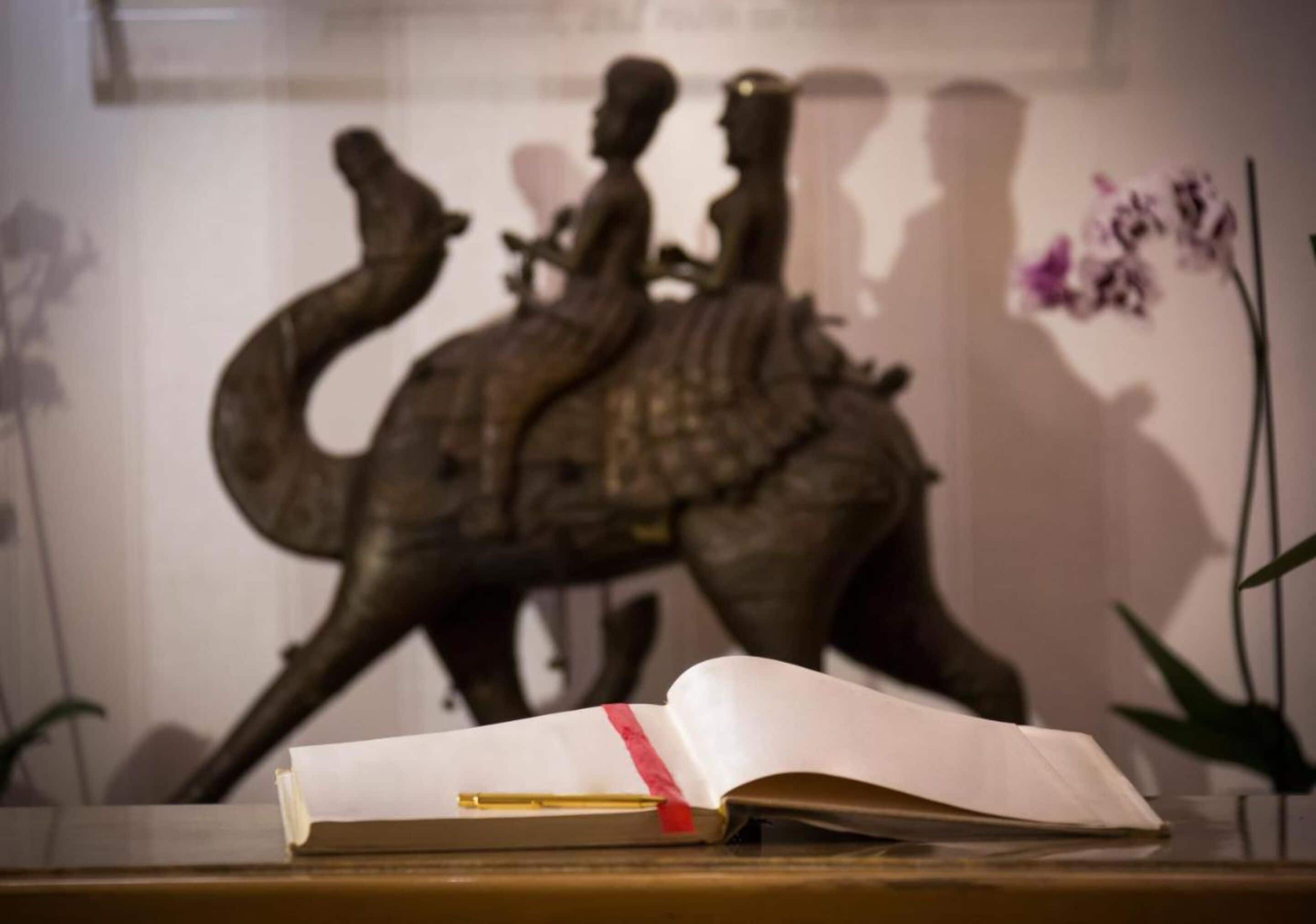 A book on a table with a sculpture in the background.