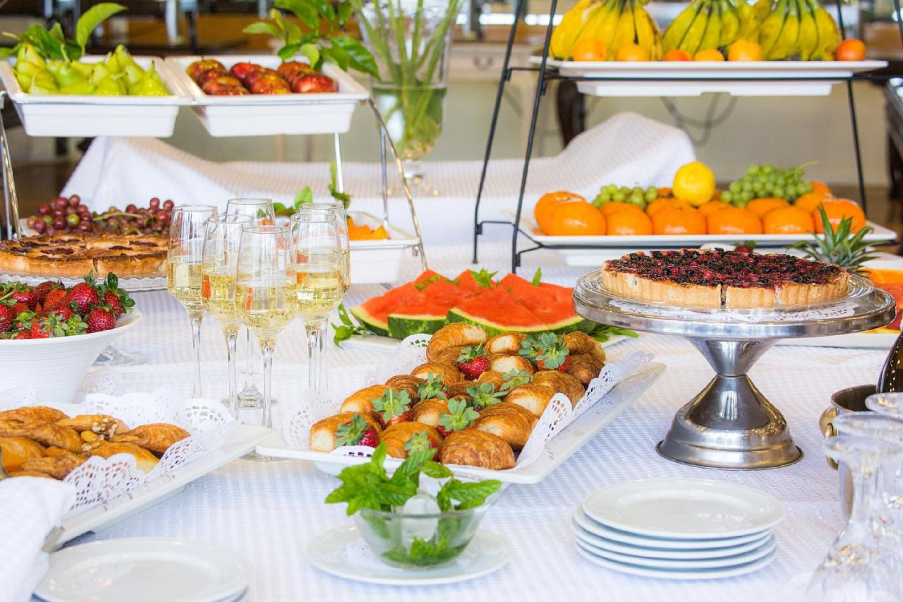 A buffet table with various food items, including fruits, pastries, and a cake.
