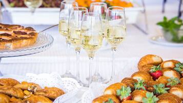 Una mesa de buffet con pasteles, croissants y copas de vino blanco.