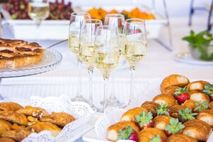 Una mesa de buffet con pasteles, croissants y copas de vino blanco.
