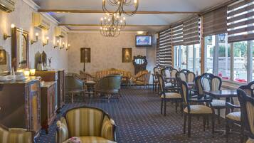 Un comedor de hotel con candelabro, mobiliario de madera y un televisor en la pared.