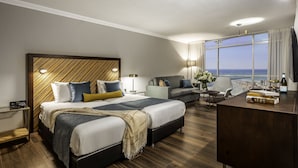 Habitación de hotel con una cama grande, un sofá, un escritorio y vistas al océano.