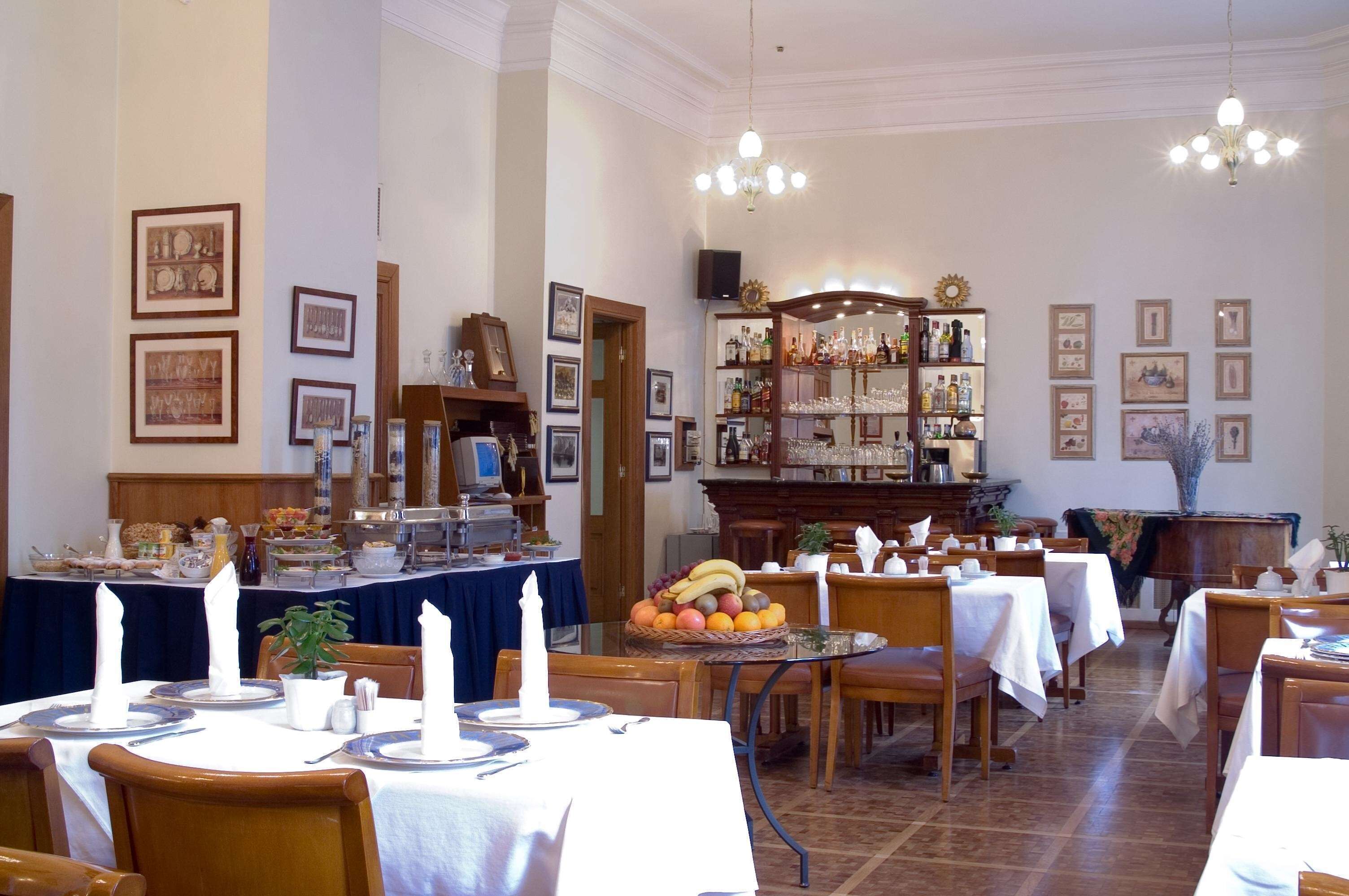 A dining area with tables set for service, a buffet with various food items, and a bar area with bottles and glasses.