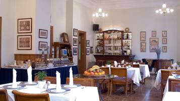 A dining area with tables set for service, a buffet with various food items, and a bar area with bottles and glasses.