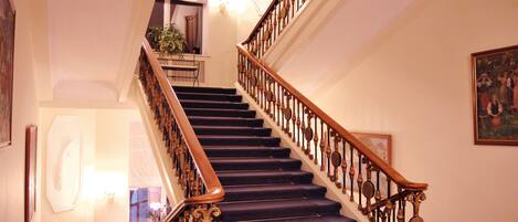 A grand staircase with ornate balusters and a dark carpeted floor.