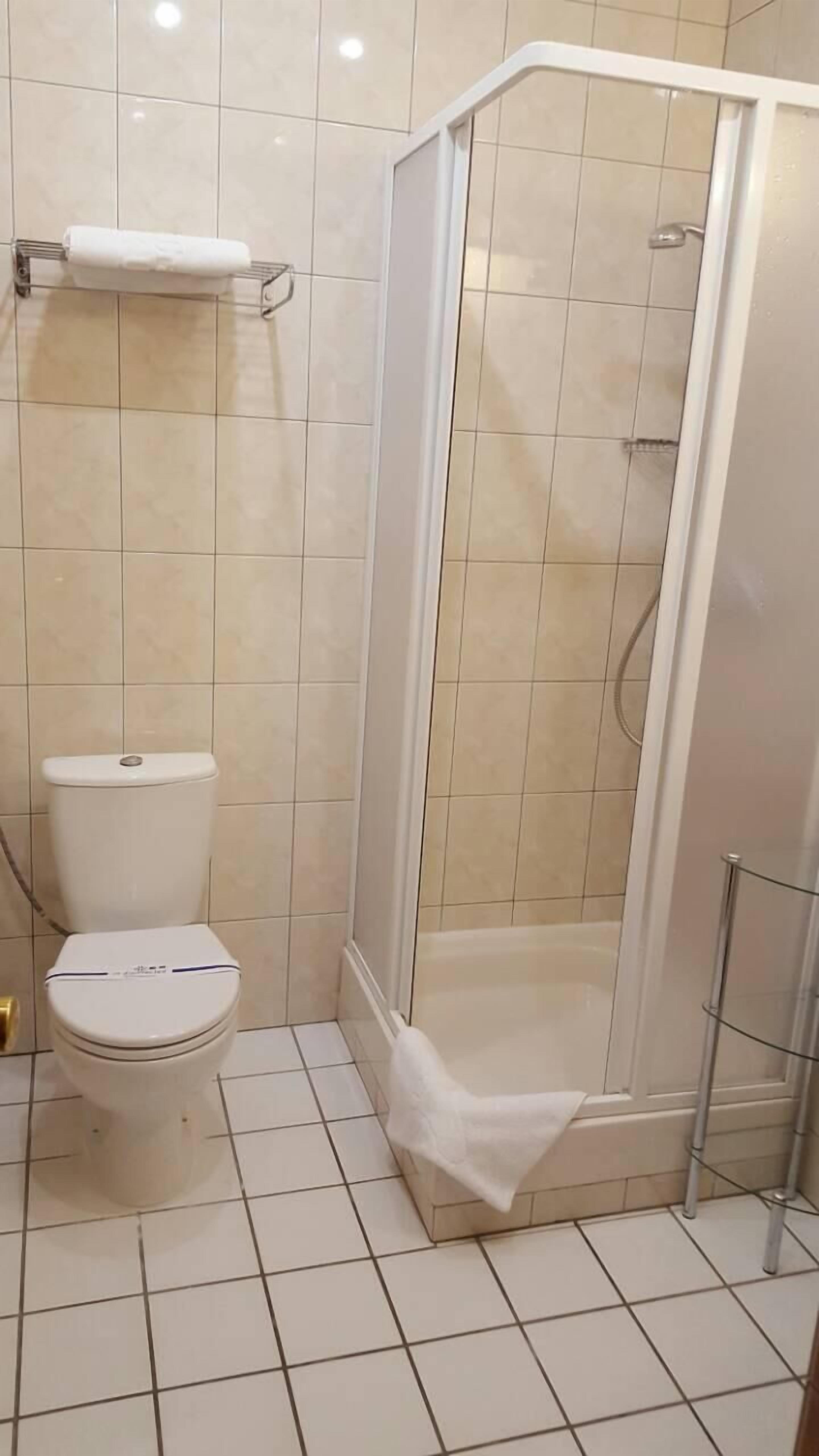 Un baño con inodoro, cabina de ducha y un perchero para toallas.