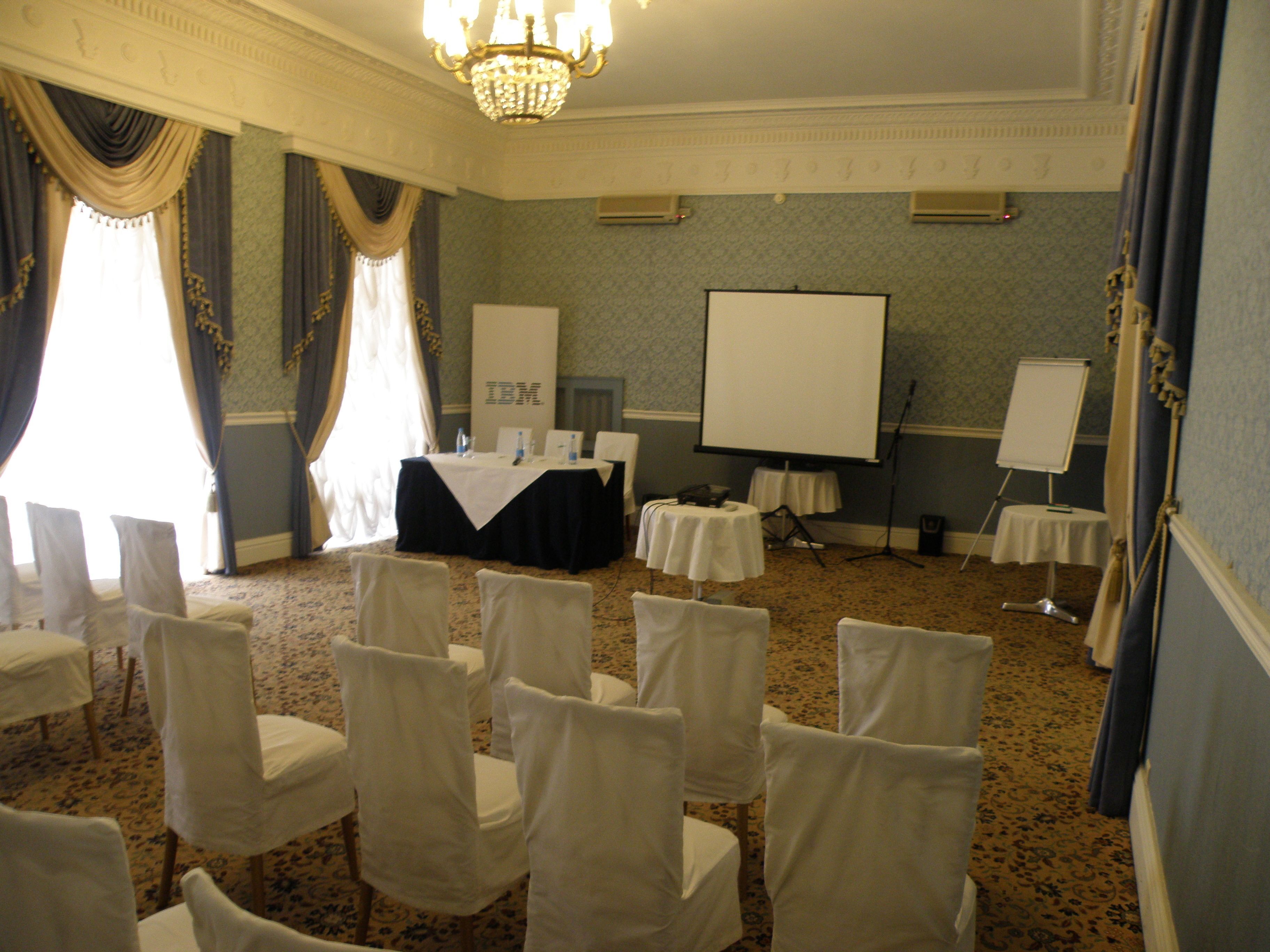 A conference room with a projector screen, tables, and chairs.