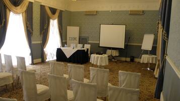 A conference room with a projector screen, tables, and chairs.