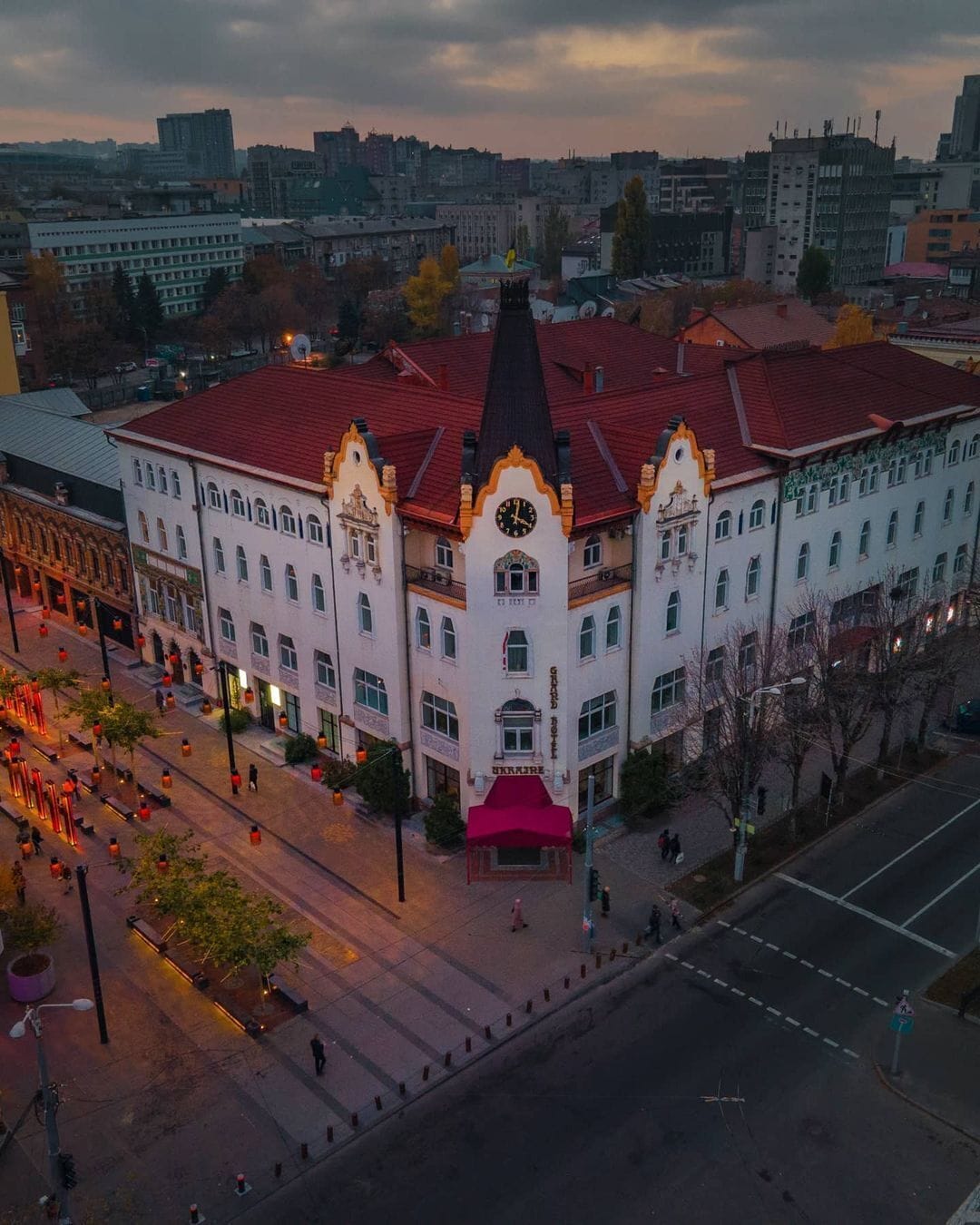 A historic building with a central clock tower, multiple windows, and a red roof.