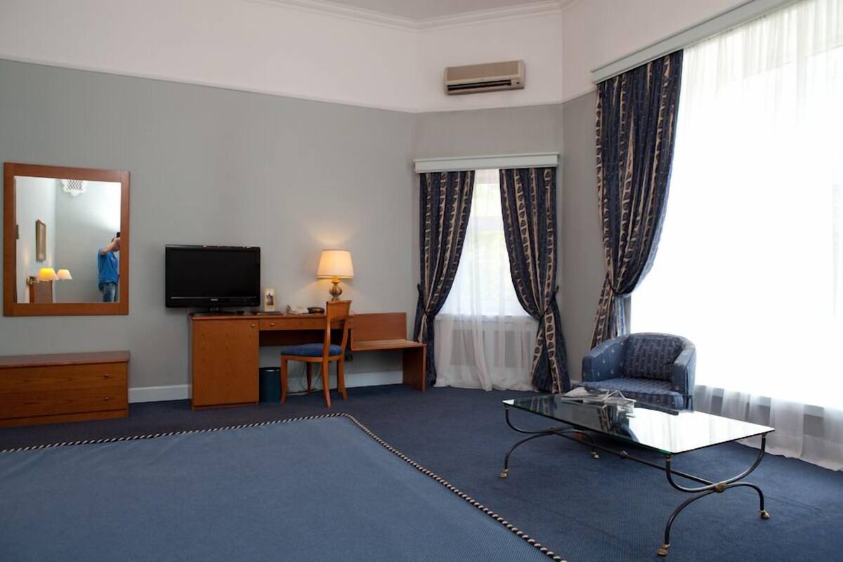 A hotel room with a desk, chair, television, and a sofa.