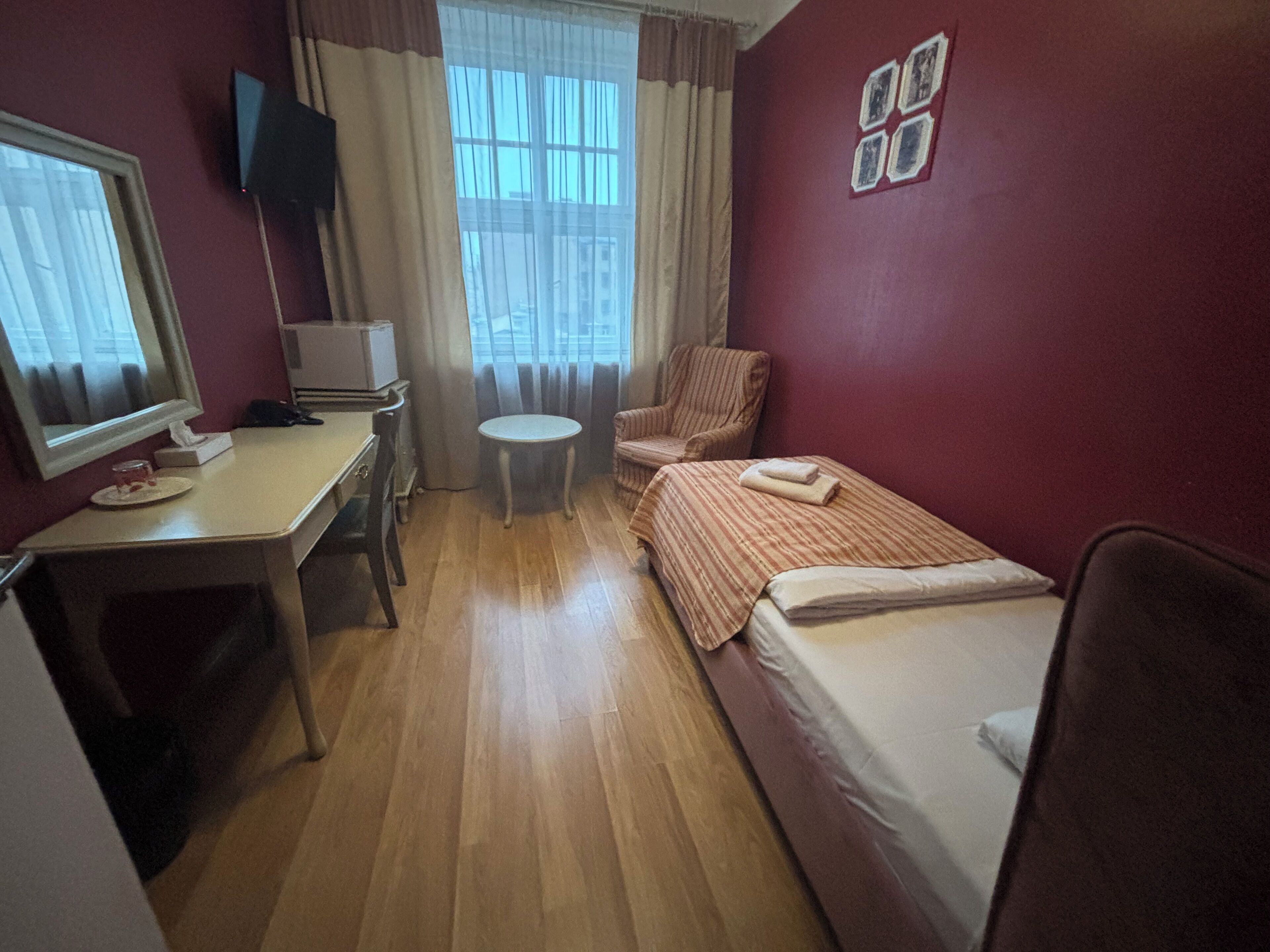 Ein Hotelzimmer mit Schreibtisch, Stuhl, Bett und einem kleinen runden Tisch.