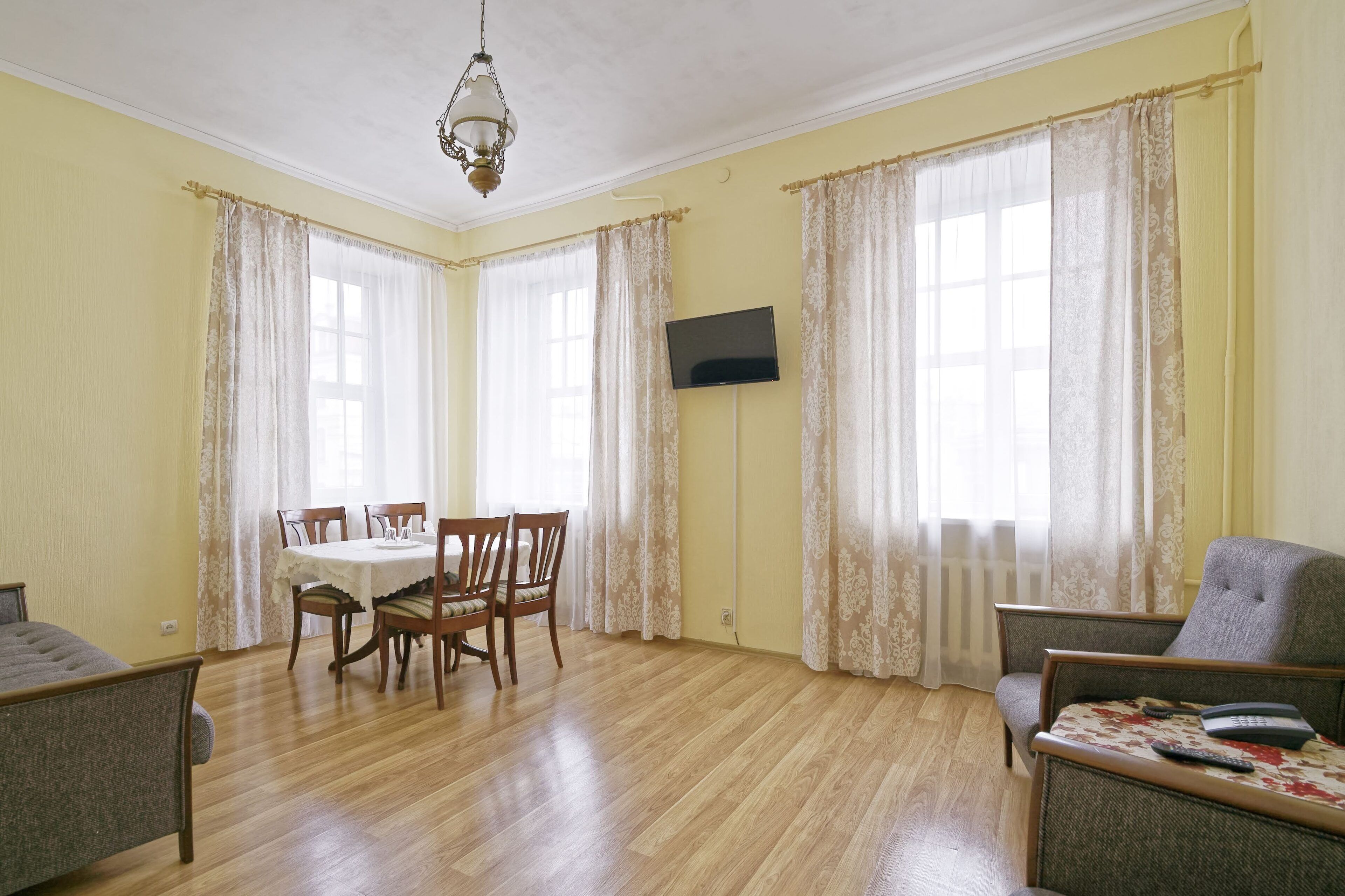 A room with a dining table, chairs, a TV, and a sofa.
