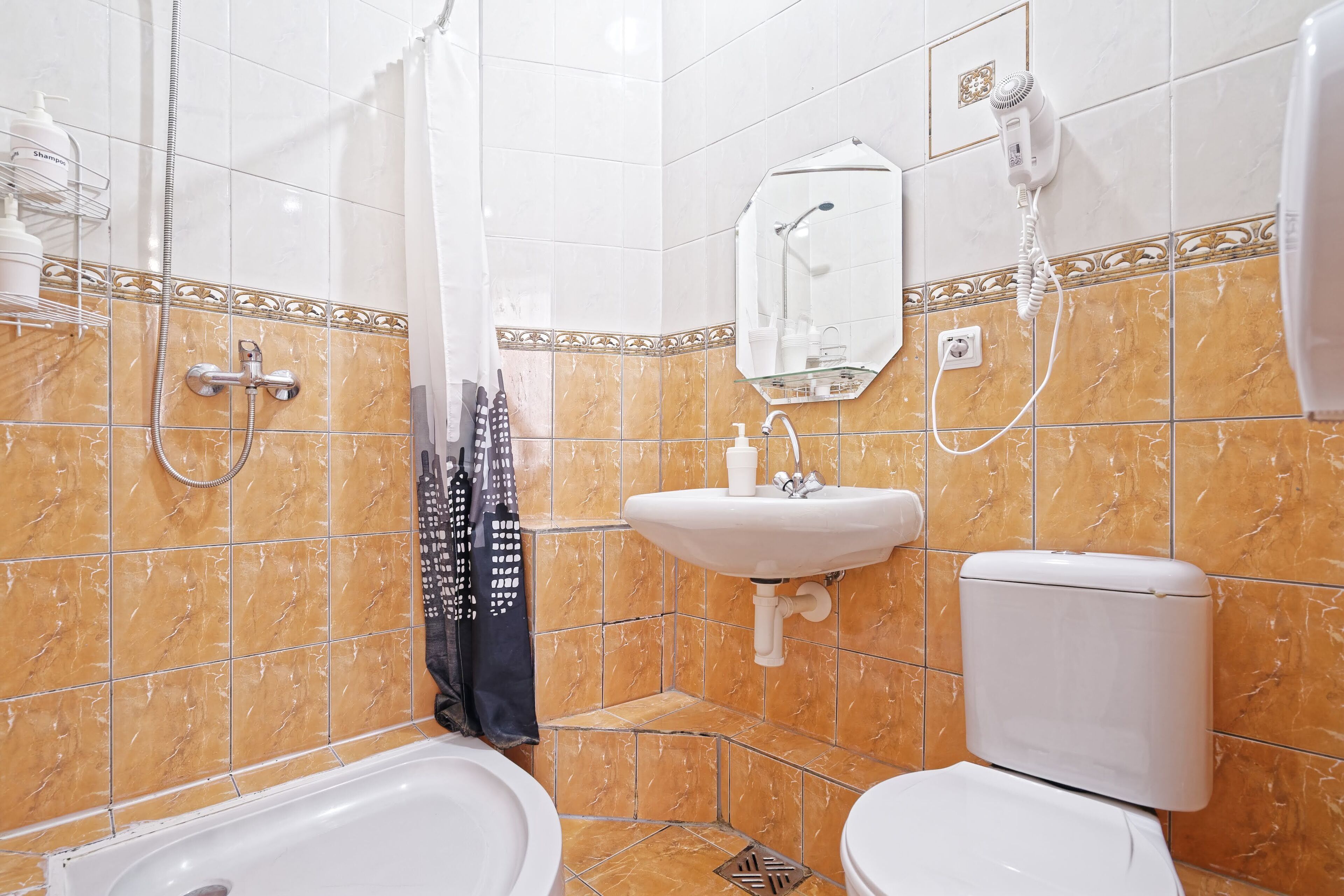 A bathroom with a shower, toilet, sink, and a hairdryer on the wall.