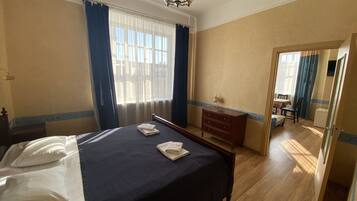 Hotellihuone, jossa on sänky, lipasto, työpöytä ja tuoli.